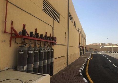 Gas suppression cylinders mounted along a building wall